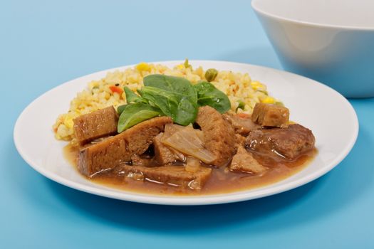 Tempeh with tomato sauce and millets on a blue background