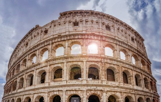 the colosseum in Rome seen from below with the bright sun between the arches