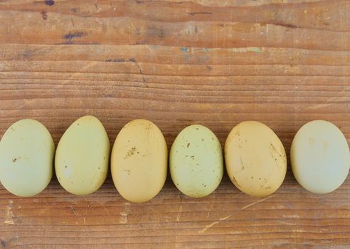 Chicken eggs in row on wooden rustic table. Top view and flat lay. Natural eggs on rural wooden background. 