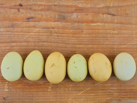 Chicken eggs in row on wooden rustic table. Top view and flat lay. Natural eggs on rural wooden background. 