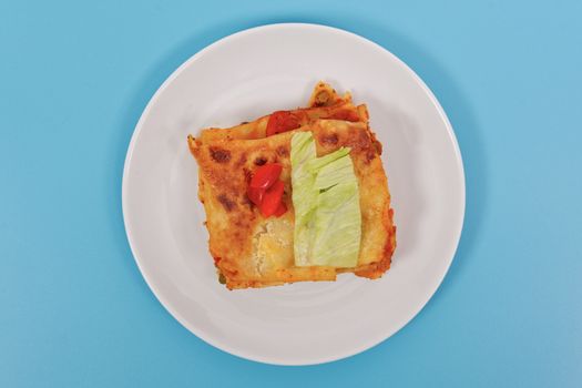 Lasagna with vegetables on a blue background