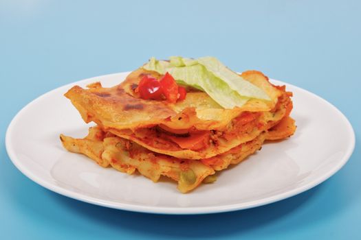 Lasagna with vegetables on a blue background