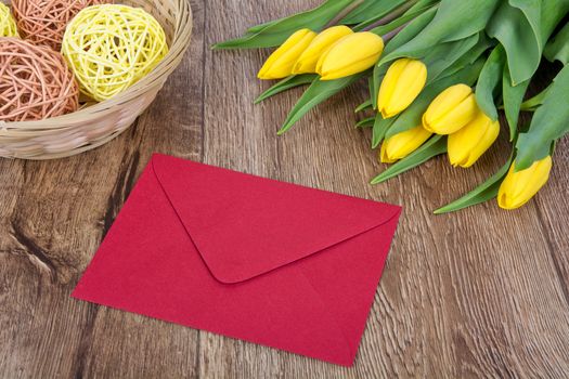 Red envelope with tulips on a wooden table
