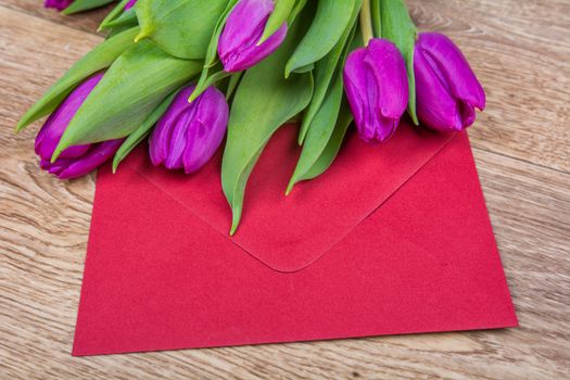 Red envelope with tulips on a wooden table