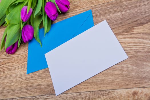 Blue envelope with tulips on a wooden table