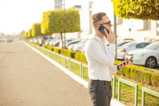 Businessman Man With Mobile Phone and Tablet computer in hands, In City, Urban Space