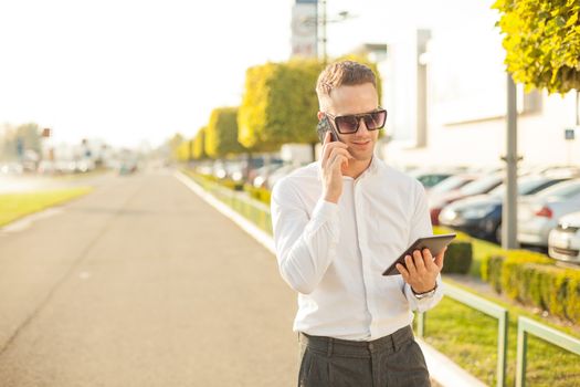 Businessman Man With Mobile Phone and Tablet computer in hands, In City, Urban Space