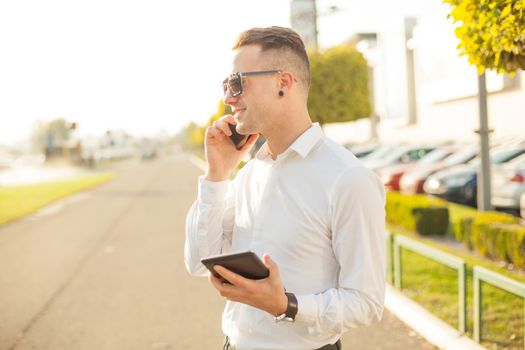 Businessman Man With Mobile Phone and Tablet computer in hands, In City, Urban Space