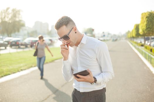 Businessman Man With Mobile Phone and Tablet computer in hands, In City, Urban Space