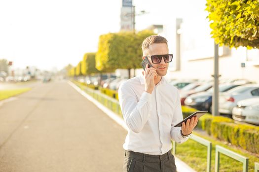 Businessman Man With Mobile Phone and Tablet computer in hands, In City, Urban Space