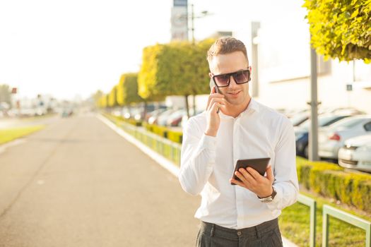 Businessman Man With Mobile Phone and Tablet computer in hands, In City, Urban Space