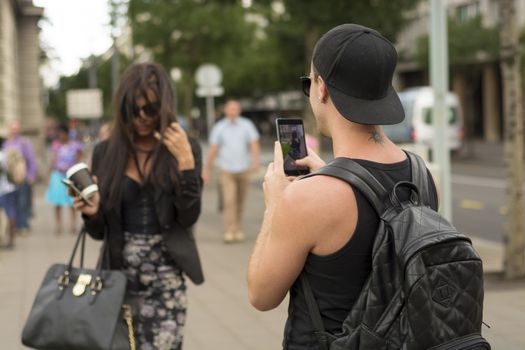 Cuple make photos on street, man photographing girl on urban space