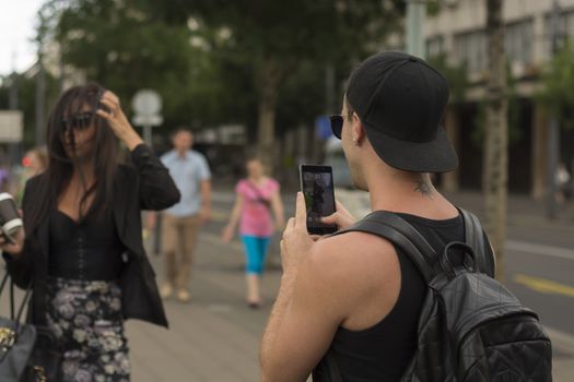 Cuple make photos on street, man photographing girl on urban space