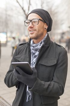 Young man reading messages and information using an i-pad tablet computer.