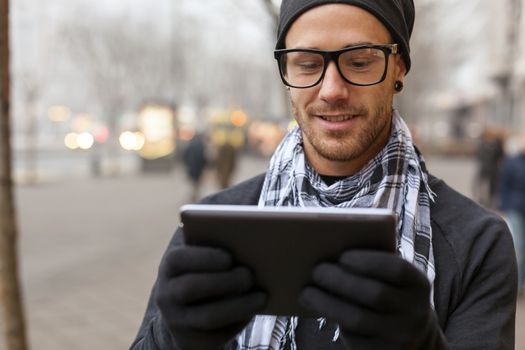 Young man reading messages and information using an i-pad tablet computer.