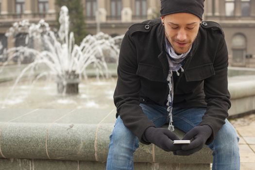 Smiling Man With Mobile Phone Read SMS In Front of Fountan, Urban Space