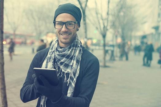 Young man reading messages and information using an i-pad tablet computer.