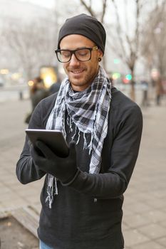 Young man reading messages and information using an i-pad tablet computer.