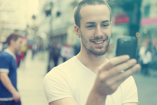 Young Man with mobile phone walking, background is blured city