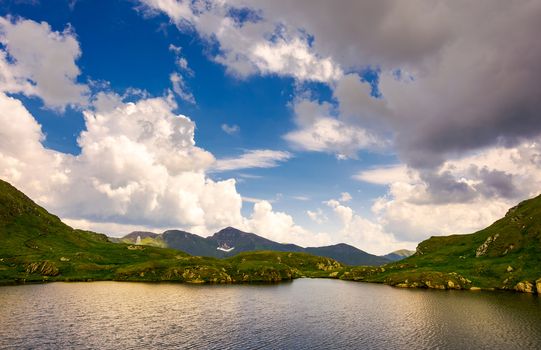 gorgeous cloudscape over the Capra lake. amazing Fagaras mountain ridge in the distance.