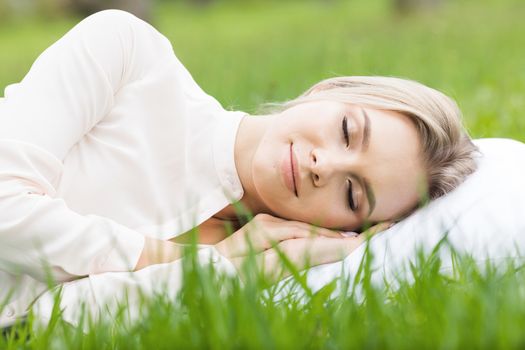 Young woman sleeping on white pillow in fresh spring grass
