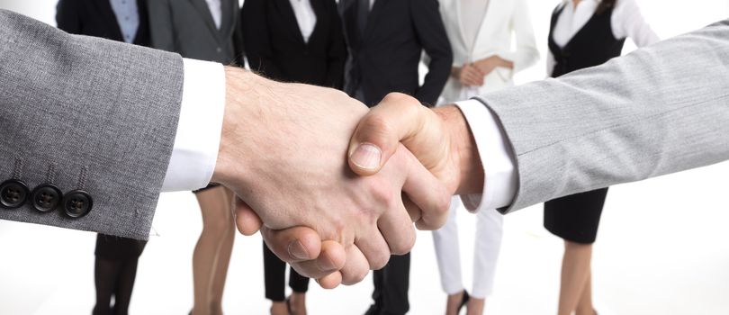 Business people shaking hands, their team standing on background