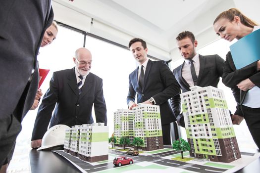 Business meeting of architects and investors looking at model of residential quarter houses
