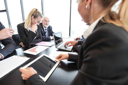 Mixed group of people at business meeting working together with documents and computers
