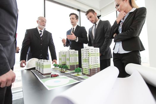 Business meeting of architects and investors looking at model of residential quarter houses