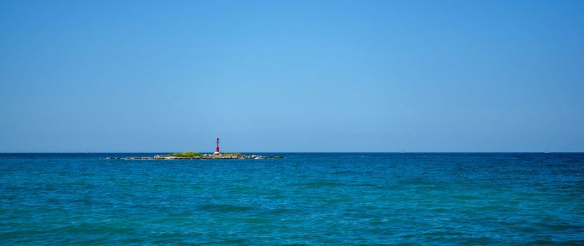 A small rocky island with a lighthouse, Adriatic sea, Mediterranean in Croatia, straight horizon line, clear blue sky