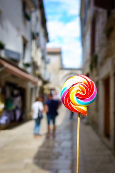 Colorful lolipop, old city street blurred as background