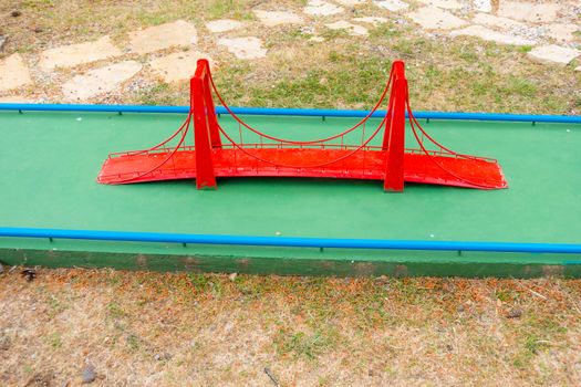 Mini golf course with obstacles, red suspension bridge