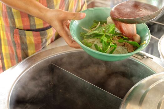 The ladle is drained in a bowl of noodles,Cooking noodle in thailand,the noodles pork and beef.