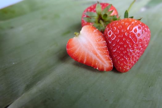 Red strawberry sliced on green banana leaf