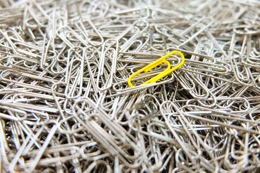 Yellow paper clip on paper clips background.
