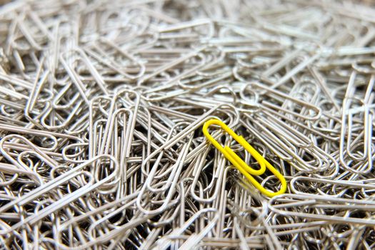 Yellow paper clip on paper clips background.