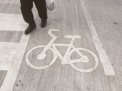 The man walking above bicycle road sign on concrete floor.