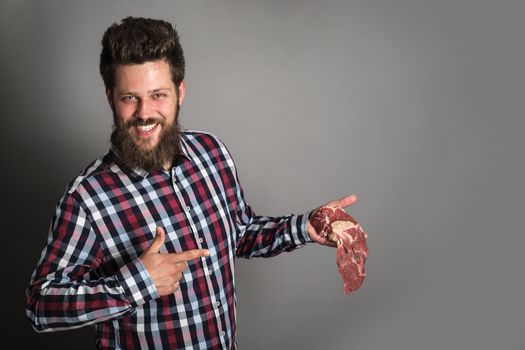 professional butcher smiling and holding raw meat. young chef demonstrating red meat