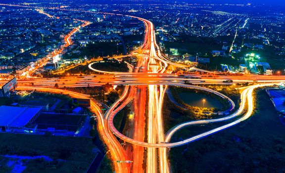 Aerial view of cityscape and traffic on highway at night.