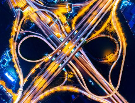 Aerial view of cityscape and traffic on highway at night.