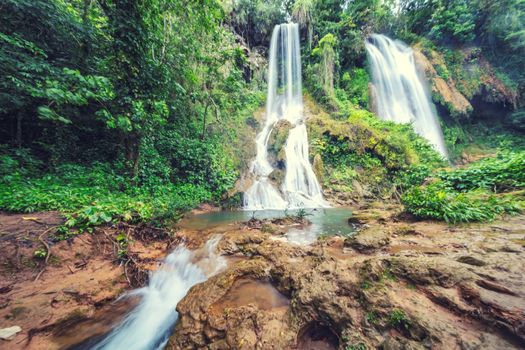 Waterfall in rainforest jungle flowing between the rocks El Rosio, river Melodioso, Guanayara park,Cuba 