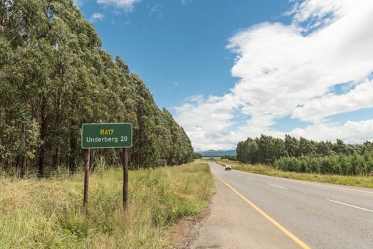 Landscape on road R617 near Underberg in the Kwazulu-Natal Province of South Africa. A distance sign, vehicle and plantation is visible