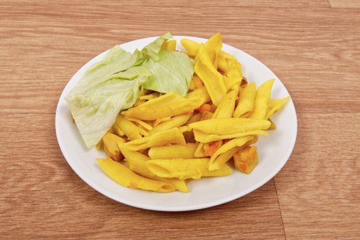 Baked pasta with curry on a wooden table