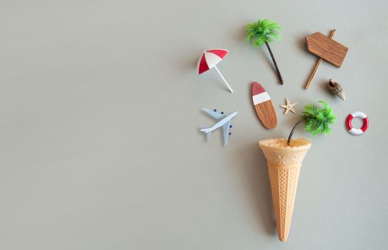 Icecream cone with various summer items including parasol, surfboard, miniature airplane and pine trees 