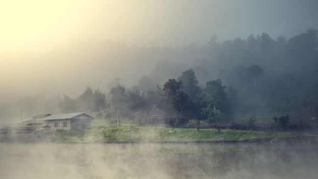 Cottage in the village among mountain and fog