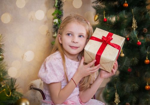 Girl with present box wondering at Christmas tree
