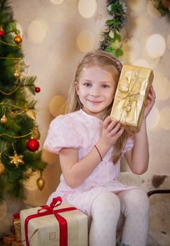 Cute girl holding present and wondering at Christmas tree