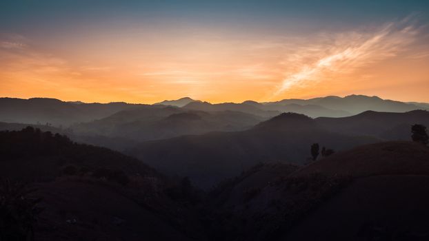 Landscape of forest mountains among mist on sunset