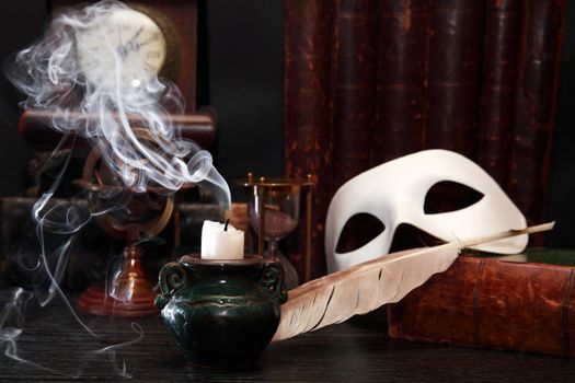 Vintage still life. Classical white Venetian mask on old book near extinguished candle