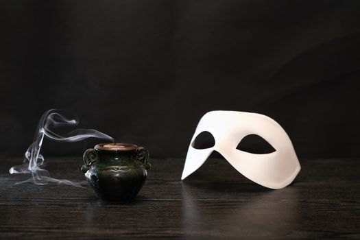 White classical Venetian mask near extinguished candle on dark background